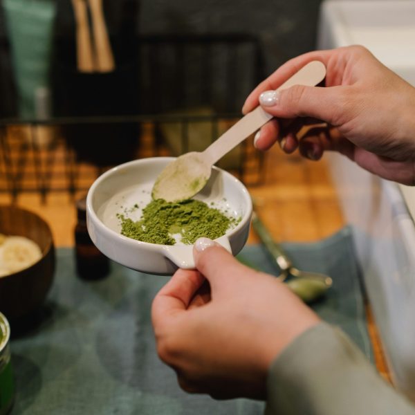 pexels-photo-6932925-6932925 Close-up of hands blending green powder for beauty treatment in a home setting.